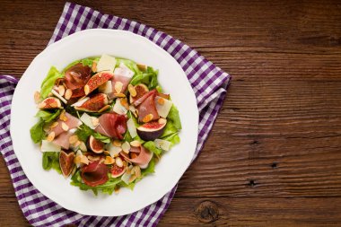 İncirli taze salata ve parmesan peynirli jambon ve kızarmış badem. Üst görünüm.