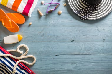 Yaz tatili teması deniz kabukları, çanta, şapka, güneş gözlüğü ve fotokopi alanı olan mavi ahşap arka plan. Üst görünüm.