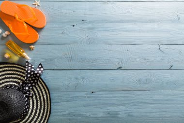 Yaz tatili teması deniz kabukları, çanta, şapka, güneş gözlüğü ve fotokopi alanı olan mavi ahşap arka plan. Üst görünüm.