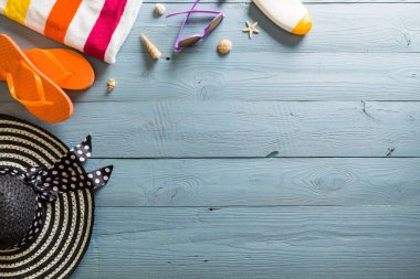 Yaz tatili teması deniz kabukları, çanta, şapka, güneş gözlüğü ve fotokopi alanı olan mavi ahşap arka plan. Üst görünüm.