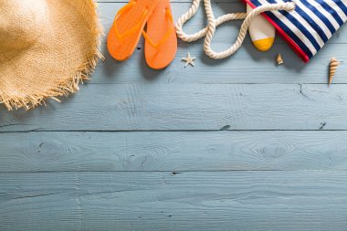 Yaz tatili teması deniz kabukları, çanta, şapka, güneş gözlüğü ve fotokopi alanı olan mavi ahşap arka plan. Üst görünüm.