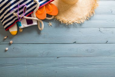 Yaz tatili teması deniz kabukları, çanta, şapka, güneş gözlüğü ve fotokopi alanı olan mavi ahşap arka plan. Üst görünüm.