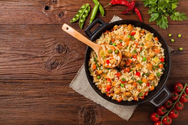 Tavuklu pilav. Bir tavada hazırlandı ve servis edildi. Arka planda doğal ahşap. Üst görünüm.