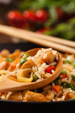 Tavuklu pilav. Bir tavada hazırlandı ve servis edildi. Arka planda doğal ahşap. Ön manzara. Kapat..