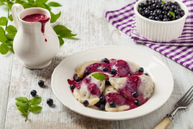 Krem şantili, şekerli ya da soslu taze yaban mersinli lezzetli hamur tatlısı. Parlak, ahşap arka plan. Ön görünüm.
