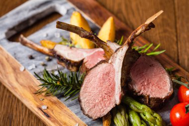 Fırında kuzu fileto, kuşkonmazla servis edilir. Koyu arkaplan.