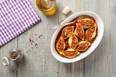 Kuru domates ve etle doldurulmuş İtalyan Conchiglioni Rigati makarnası. Peynir serpilmiş. Üst görünüm.