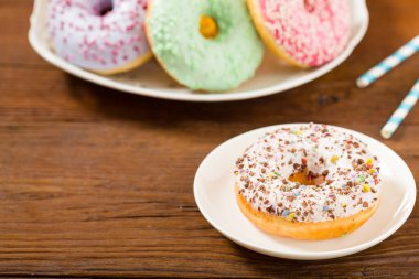 Ahşap arka planda renkli çörekler. Ön görünüm.