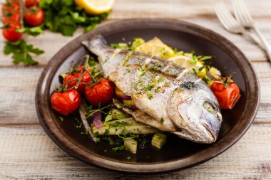 Fırında balık, kızarmış sebze ve limonla servis ediliyor. Ön görünüm.