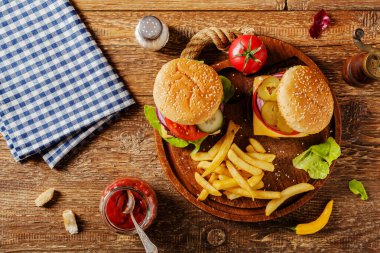 Ev yapımı, peynirli ve sebzeli sığır burger. Patates kızartmasıyla servis edilmiş. Üst görünüm.