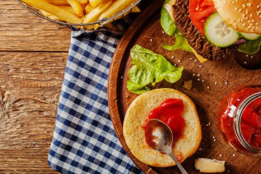 Ev yapımı, peynirli ve sebzeli sığır burger. Patates kızartmasıyla servis edilmiş. Üst görünüm.