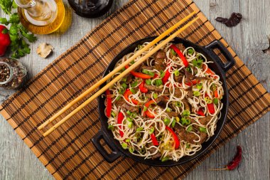 Sığır etli Çin makarnası. Tavada hazır. Ahşap arka plan. Üst görünüm.