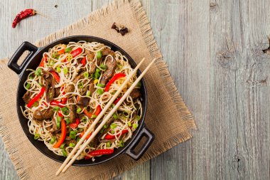 Sığır etli Çin makarnası. Tavada hazır. Ahşap arka plan. Üst görünüm.
