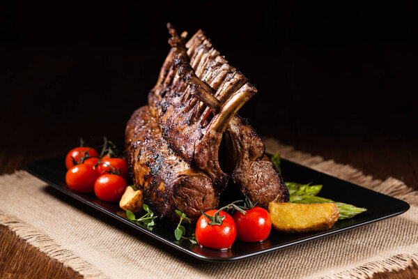 Запеченный ягненок, подается со спаржей. Темный фон.