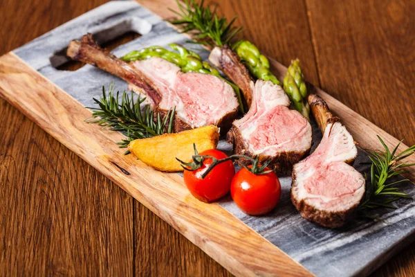 Baked lamb loin, served with asparagus. Dark background.