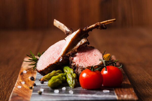 Запеченный ягненок, подается со спаржей. Темный фон.