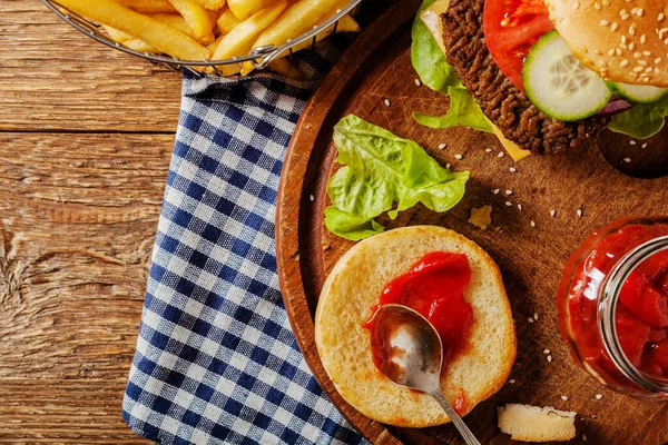 Ev yapımı, peynirli ve sebzeli sığır burger. Patates kızartmasıyla servis edilmiş. Üst görünüm.