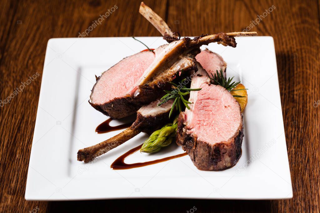 Baked lamb loin, served with asparagus. Dark background.