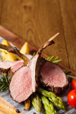 Fırında kuzu fileto, kuşkonmazla servis edilir. Koyu arkaplan.