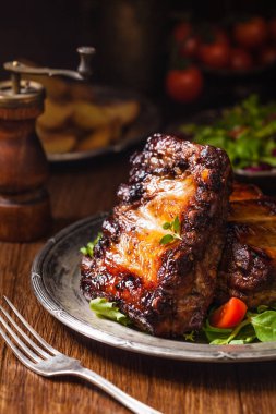 Kızarmış pirzola, eski bir tabakta servis edilir. Fron manzaralı. Koyu veya kel arkaplan.