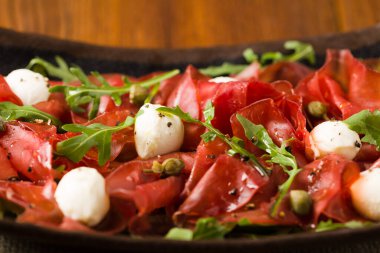 Biftek carpaccio mozzarella peyniri, roka ve kapari ile servis edilir. Ön manzara. Yakın plan..