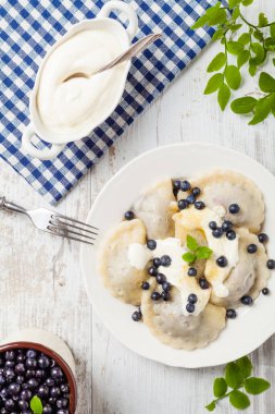 Krem şantili, şekerli ya da soslu taze yaban mersinli lezzetli hamur tatlısı. Parlak, ahşap arka plan. Üst görünüm.