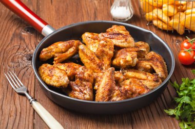 Fırında kanat, sos ya da fırında patates ile servis edilir. Ön görünüm.