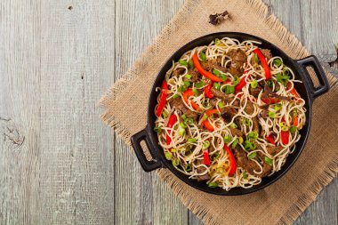 Sığır etli Çin makarnası. Tavada hazır. Ahşap arka plan. Üst görünüm.