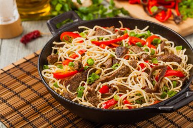 Sığır etli Çin makarnası. Tavada hazır. Ahşap arka plan. Ön görünüm.