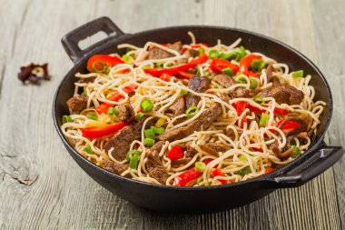 Sığır etli Çin makarnası. Tavada hazır. Ahşap arka plan. Ön görünüm.