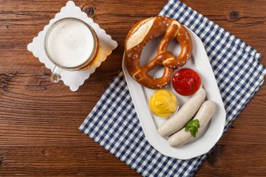Kaynamış beyaz sosis, bira ve krakerle servis edilir. Ekim Festivali için mükemmel. Doğal ahşap arka plan. Üst görünüm. 