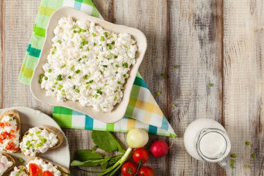 Taze süzme peynir, taze sebze ve kremayla servis edilir. Üst görünüm.