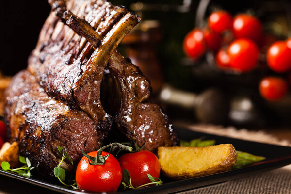 Запеченный ягненок, подается со спаржей. Темный фон.