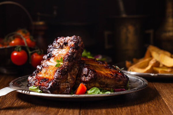 Roasted ribs, served on an old plate. Fron view. Dark or balck background.