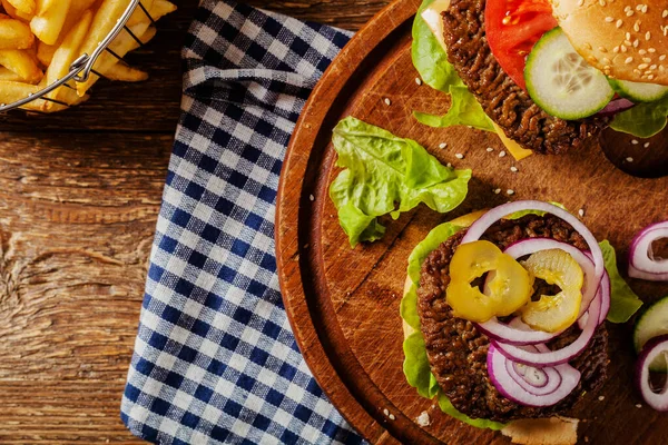 Ev yapımı, peynirli ve sebzeli sığır burger. Patates kızartmasıyla servis edilmiş. Üst görünüm.