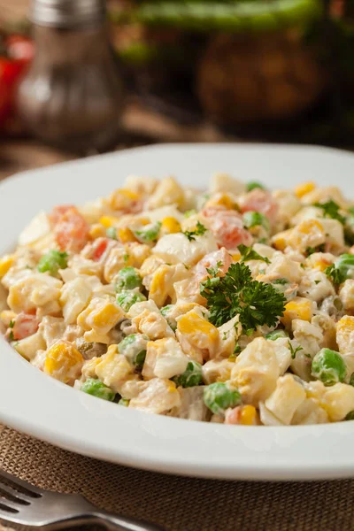 Traditional salad with cooked vegetables with mayonnaise. Wooden background. Front view.