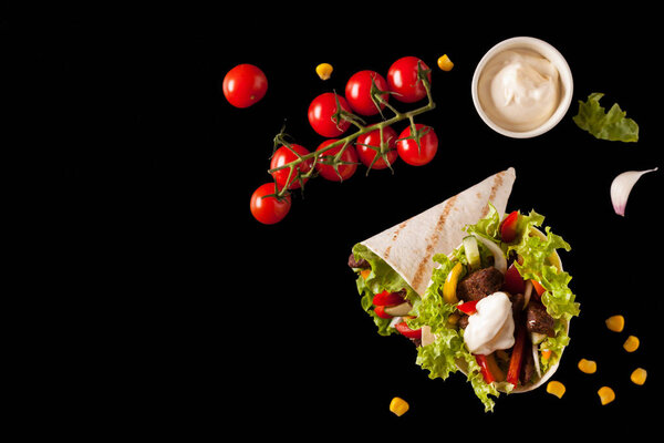 Tortilla with beef. Top view. Black background.