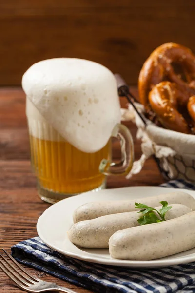 Boiled white sausages, served with beer and pretzels. Perfect for Octoberfest. Natural wooden background. Front view.