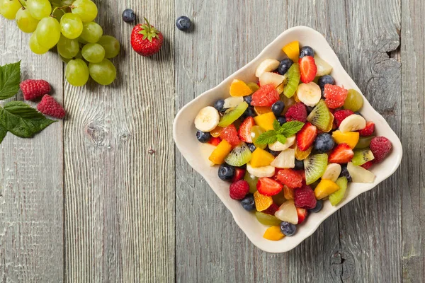 新鮮な果物とおいしいフルーツサラダ 木製の背景にグレーのテーブル トップ表示 — ストック写真