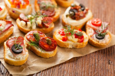 Ahşap arka planda farklı malzemelerle Crostini. Lezzetli aperatifler. Ön görünüm.
