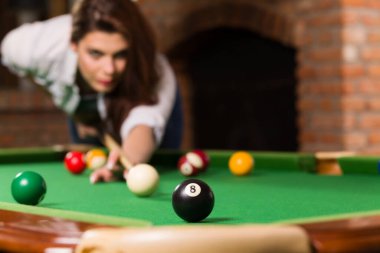 Bilardo oynayan genç bir kadın.