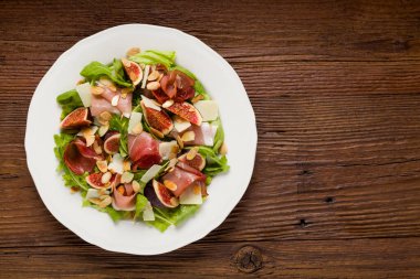 İncirli taze salata ve parmesan peynirli jambon ve kızarmış badem. Üst görünüm.