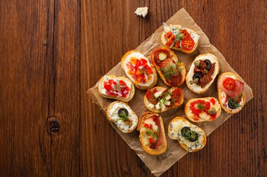 Ahşap arka planda farklı malzemelerle Crostini. Lezzetli aperatifler. Üst görünüm.