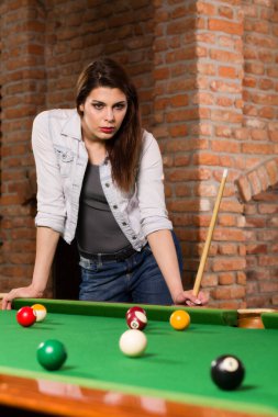 Bilardo oynayan genç bir kadın.