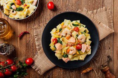 Geleneksel İtalyan fettuccini ile somon, karides ve ıspanak. Doğal tahta arka plan. Üst görünüm.