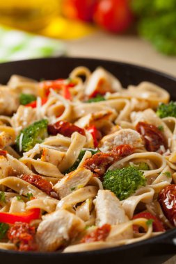 Kızarmış tavuk, kurutulmuş domates ve brokoli ile tam tahıllı tagliatelle makarna. Bir kanepede hizmet etti. Ön görünüm.