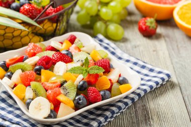 Taze meyveli lezzetli meyve salatası. Arkadaki tahta, gri masa. Ön görünüm.