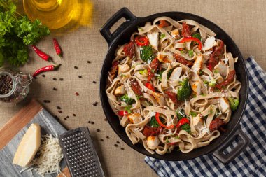 Kızarmış tavuk, kurutulmuş domates ve brokoli ile tam tahıllı tagliatelle makarna. Bir kanepede hizmet etti. Üst görünüm.