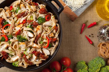 Kızarmış tavuk, kurutulmuş domates ve brokoli ile tam tahıllı tagliatelle makarna. Bir kanepede hizmet etti. Üst görünüm.