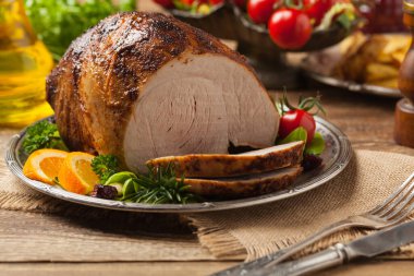 Fırında jambon, eski bir tabakta servis edilir. Doğal ahşap arka plan. Ön görünüm.